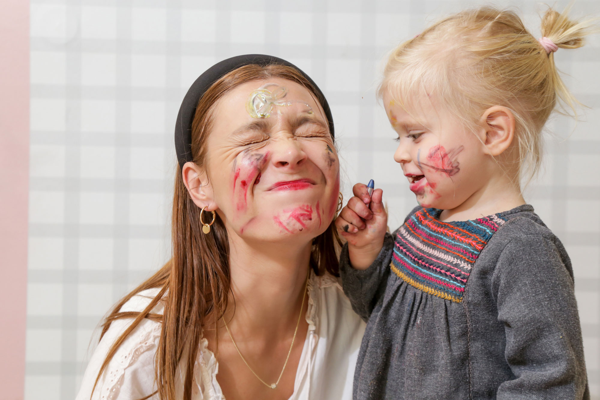 a girl drawing on a womans face with paint